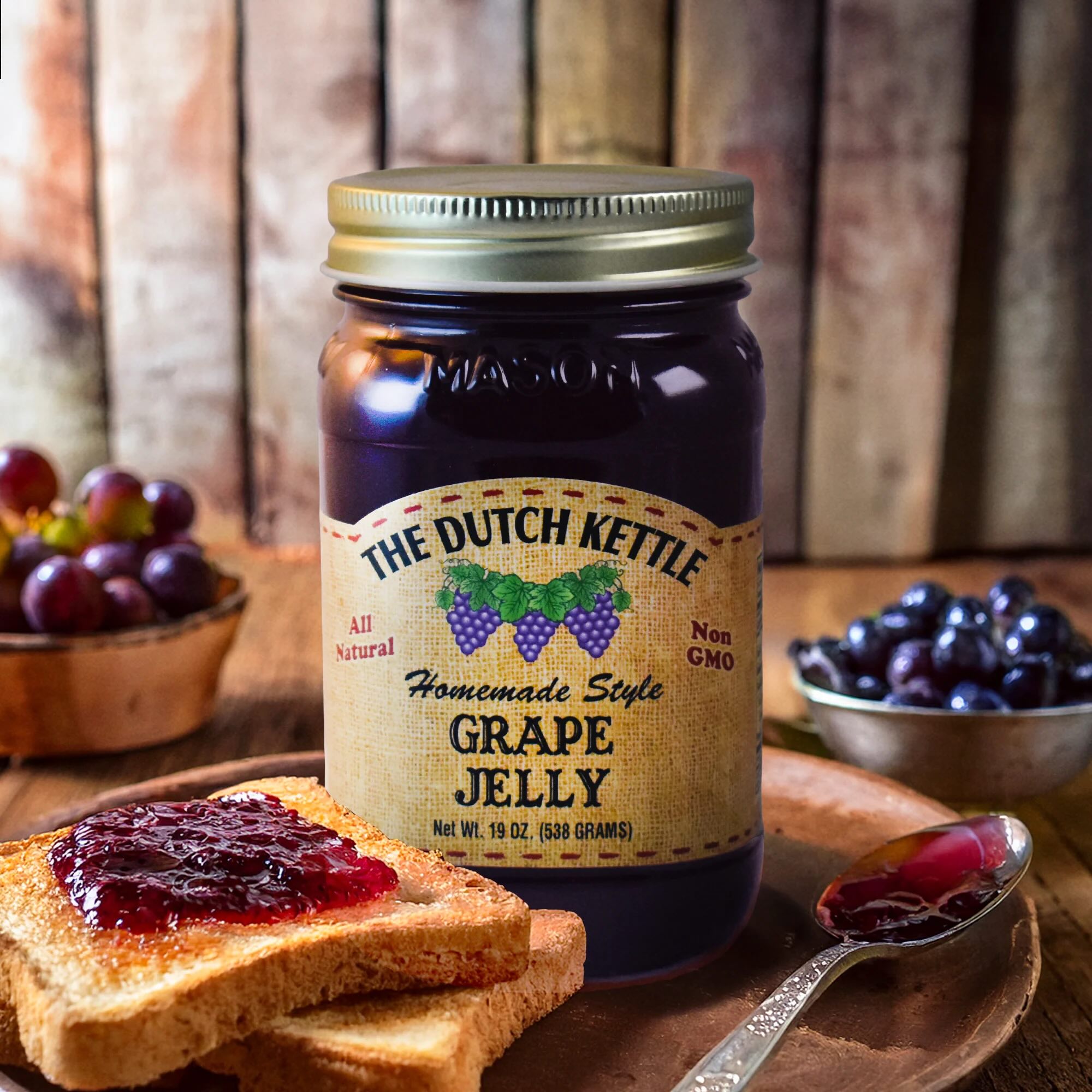 The Dutch Kettle homemade style grape jelly jar on a plate with toast with grape jelly, grapes, and a rustic background.