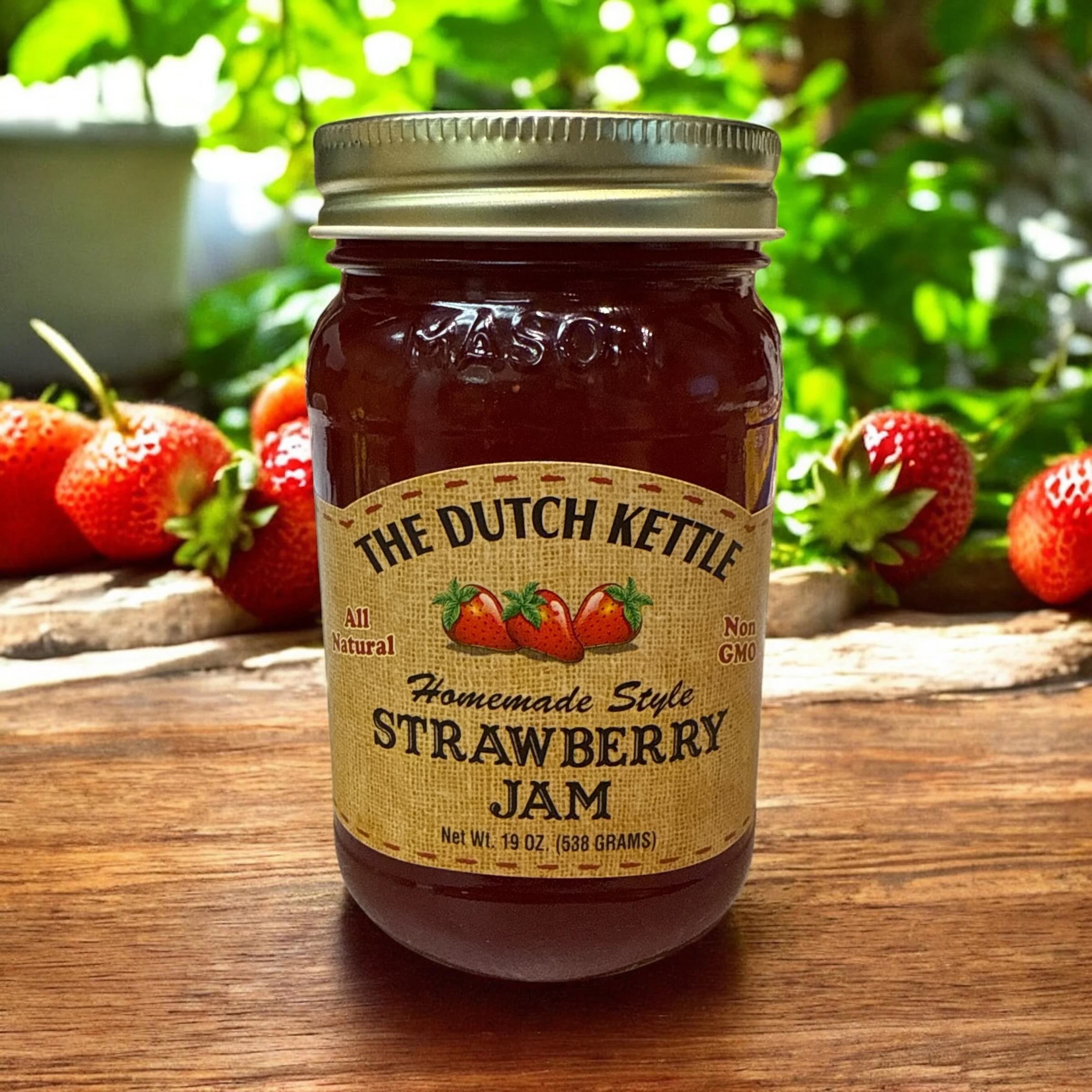 The Dutch Kettle homemade style amish strawberry jam on a wooden table with strawberries.