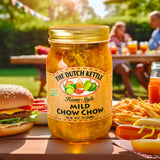 The Dutch Kettle Amish Homestyle Mild Chow Chow on a table with cheeseburger and hot dog and fries at a cookout. 