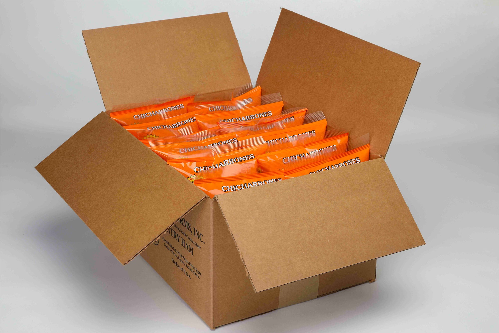 Cardboard box filled with 8 Pork Skins Bar-B-Q flavor bags on a gray background.
